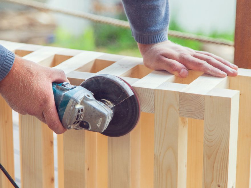 crop unrecognizable carpenter polishing wooden construction with grinding machine