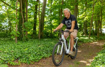 a man riding an electric bicycle on dirt path in the woods