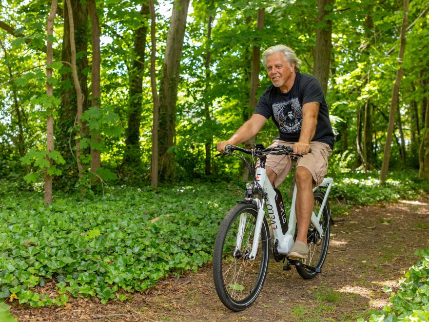 a man riding an electric bicycle on dirt path in the woods