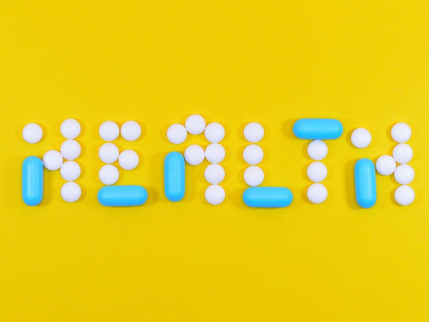 white and blue health pill and tablet letter cutout on yellow surface
