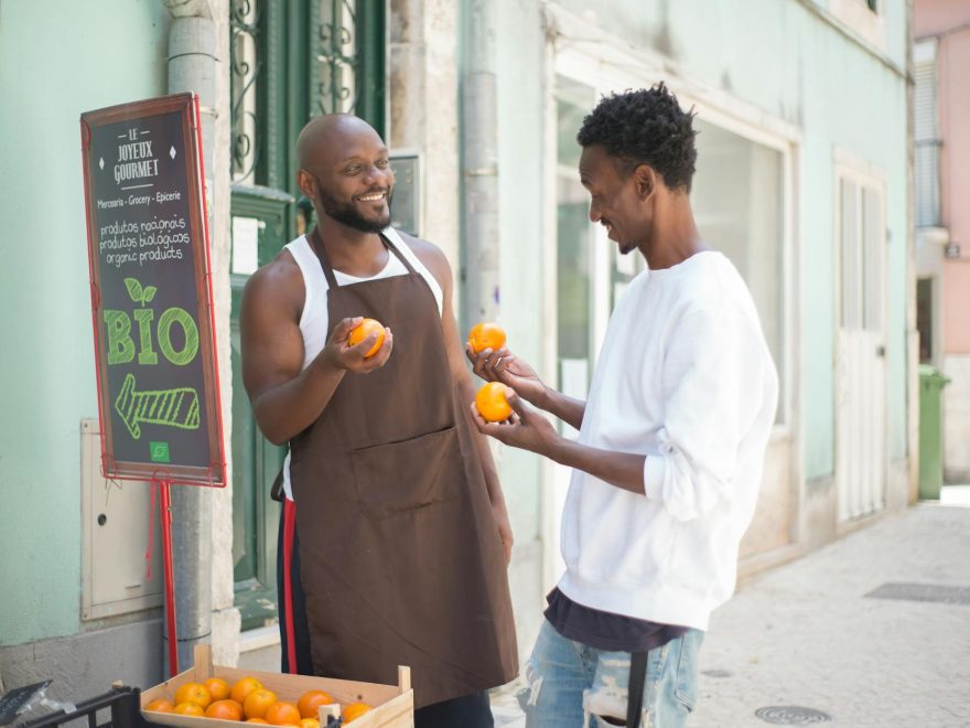 a seller talking to his customer while holding orange fruits